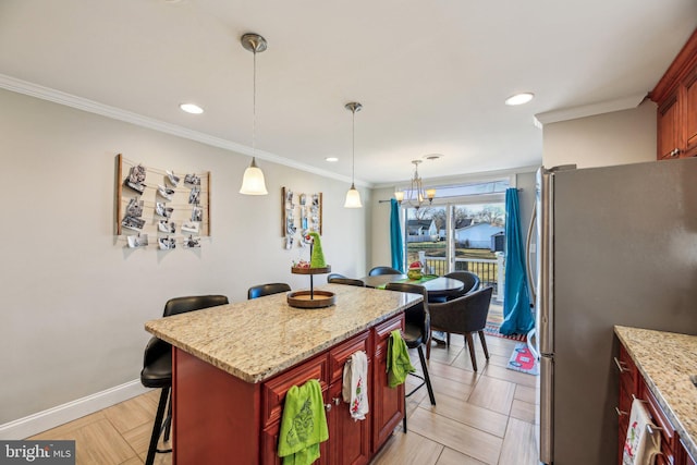 kitchen with light stone countertops, stainless steel fridge, crown molding, a kitchen bar, and a kitchen island