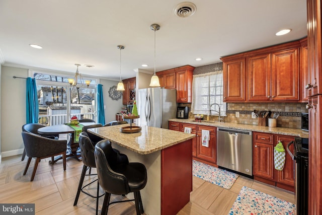 kitchen with a breakfast bar, decorative light fixtures, a kitchen island, light stone counters, and stainless steel appliances