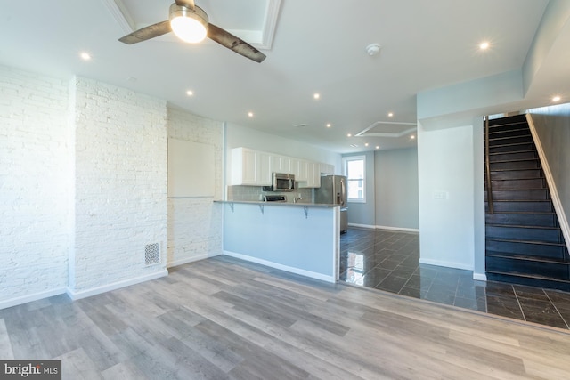 kitchen with kitchen peninsula, white cabinets, stainless steel appliances, and hardwood / wood-style flooring