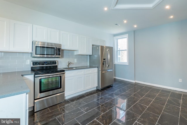 kitchen featuring white cabinets, appliances with stainless steel finishes, backsplash, and sink