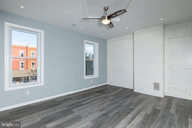 unfurnished bedroom with dark hardwood / wood-style flooring, ceiling fan, and brick wall