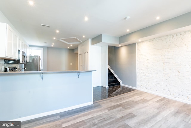 kitchen with white cabinetry, stainless steel appliances, dark hardwood / wood-style floors, kitchen peninsula, and a breakfast bar area