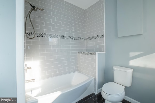 bathroom with tile patterned floors, tiled shower / bath combo, and toilet