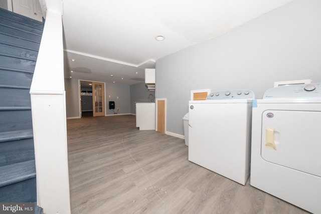 laundry room with washer and dryer, light hardwood / wood-style floors, and sink