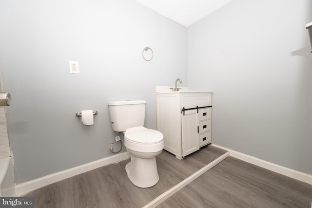 bathroom with a washtub, hardwood / wood-style floors, vanity, and toilet