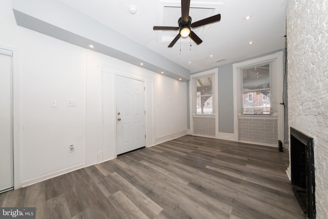 unfurnished living room featuring a fireplace, ceiling fan, and dark wood-type flooring