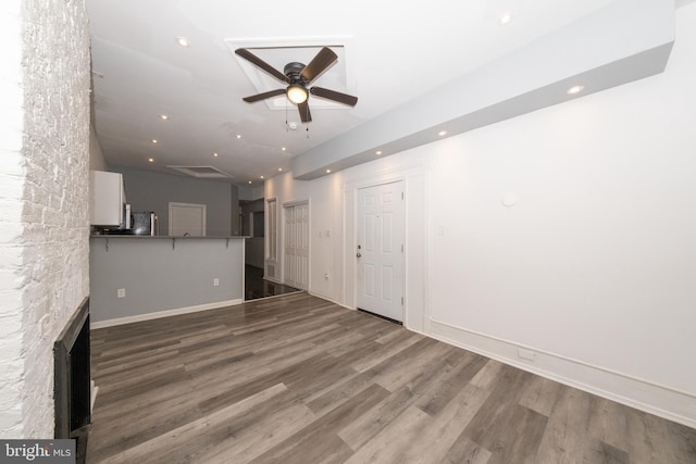 unfurnished living room featuring hardwood / wood-style floors, ceiling fan, and a stone fireplace