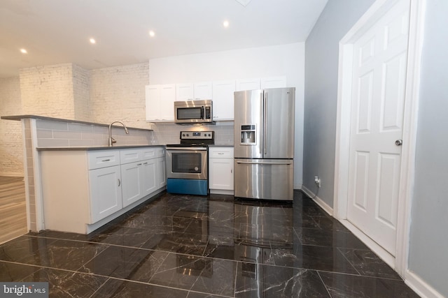 kitchen featuring kitchen peninsula, appliances with stainless steel finishes, tasteful backsplash, sink, and white cabinetry