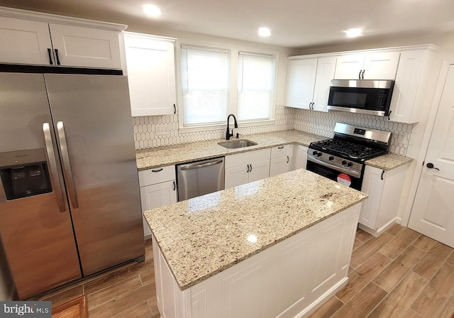 kitchen featuring light stone countertops, appliances with stainless steel finishes, white cabinets, and sink