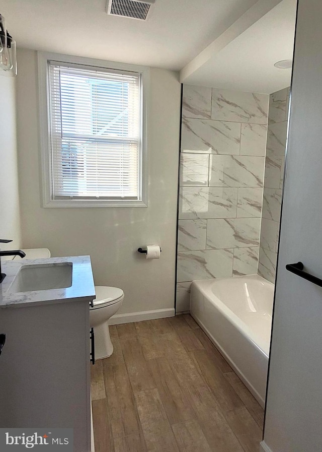 full bathroom featuring vanity, hardwood / wood-style flooring, toilet, and tiled shower / bath combo