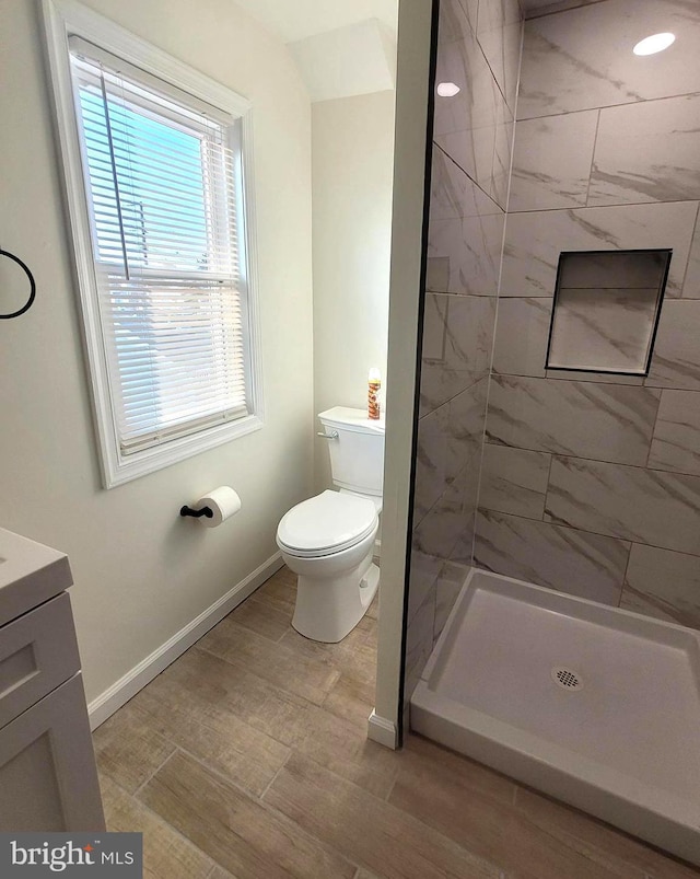 bathroom featuring toilet, vanity, and tiled shower