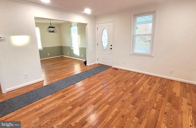 foyer entrance featuring hardwood / wood-style flooring, ornamental molding, and a notable chandelier