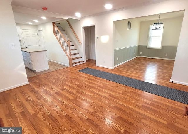 unfurnished living room featuring crown molding and light hardwood / wood-style flooring