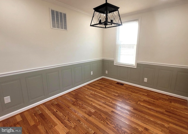 unfurnished dining area featuring hardwood / wood-style flooring, ornamental molding, and a notable chandelier