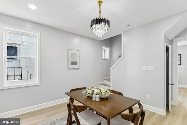 dining area with light hardwood / wood-style flooring and a notable chandelier