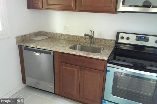 kitchen with light stone counters, sink, light tile patterned floors, and stainless steel appliances