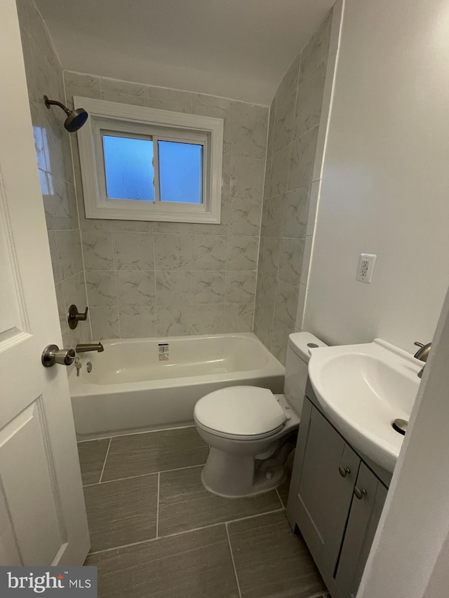 full bathroom featuring tiled shower / bath, vanity, and toilet