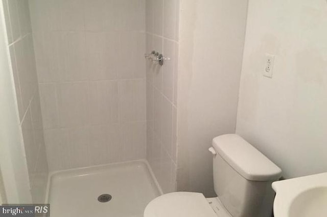 bathroom with tiled shower and toilet