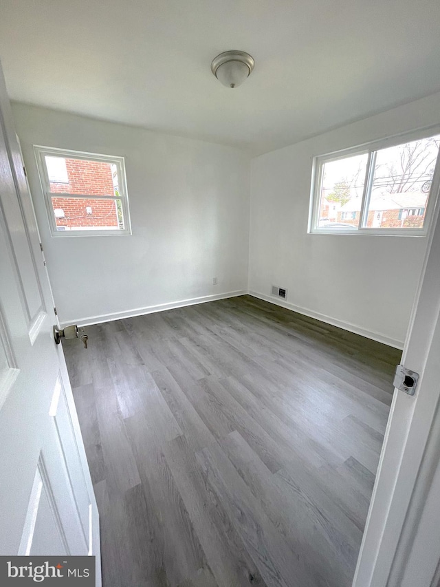 spare room with a healthy amount of sunlight and hardwood / wood-style flooring