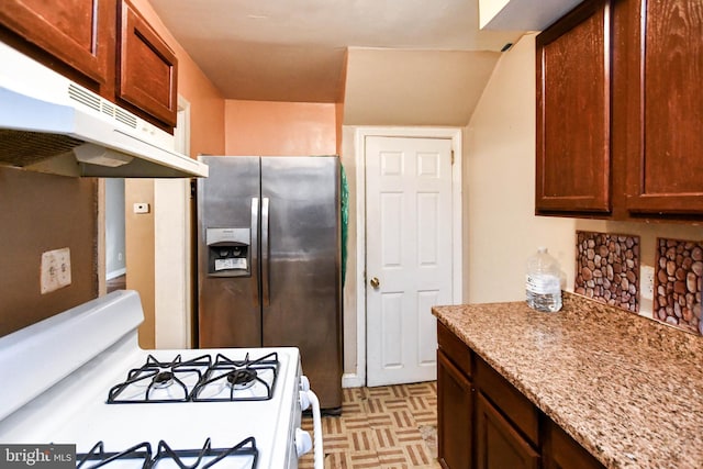 kitchen with white range with gas stovetop, stainless steel refrigerator with ice dispenser, and light stone counters