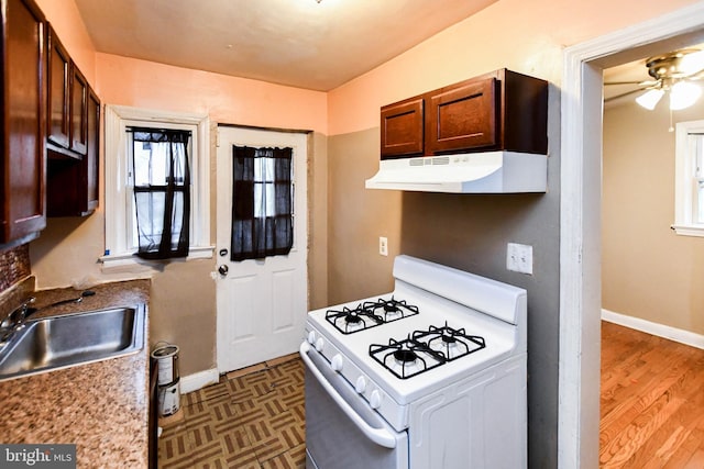 kitchen with ceiling fan, dark hardwood / wood-style flooring, sink, and white range with gas cooktop