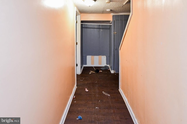 corridor with dark hardwood / wood-style flooring and a textured ceiling