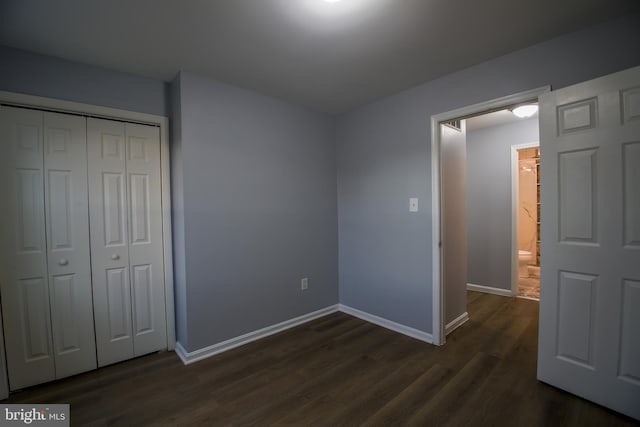 unfurnished bedroom with baseboards, dark wood finished floors, and a closet