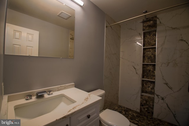 bathroom featuring toilet, a marble finish shower, visible vents, and vanity