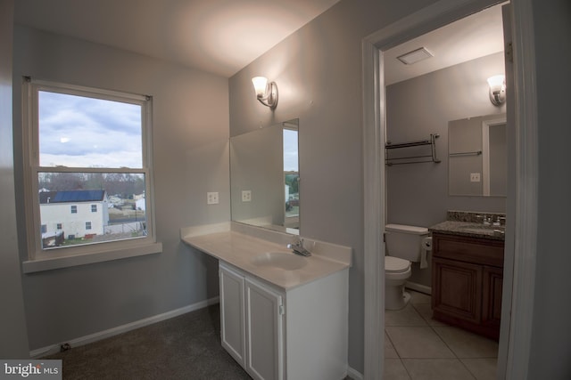 bathroom featuring toilet, baseboards, two vanities, and a sink