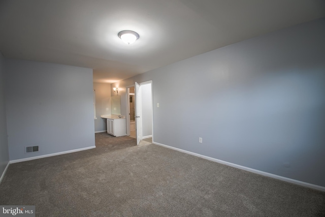 unfurnished bedroom featuring ensuite bathroom, carpet flooring, visible vents, and baseboards