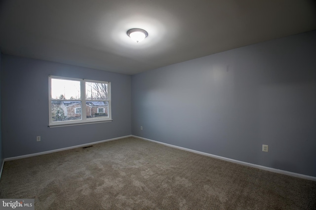 carpeted empty room featuring baseboards and visible vents