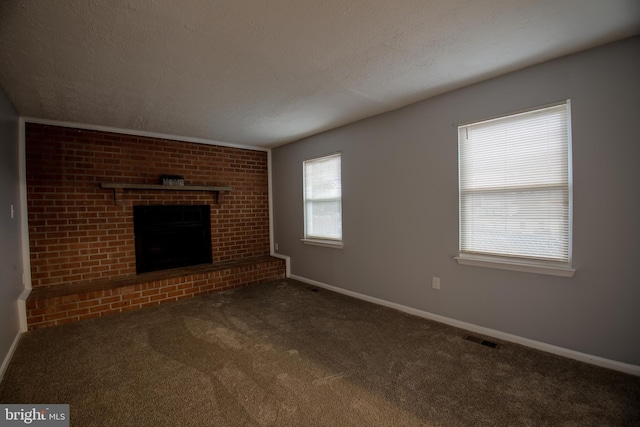 unfurnished living room with carpet, a fireplace, visible vents, a textured ceiling, and baseboards