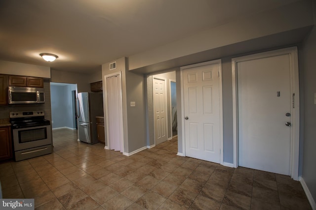 kitchen featuring appliances with stainless steel finishes, tile patterned floors, visible vents, and baseboards