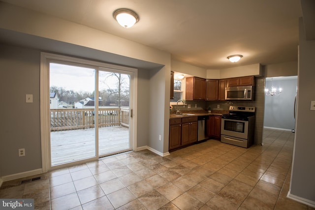 kitchen with baseboards, visible vents, a sink, stainless steel appliances, and a notable chandelier