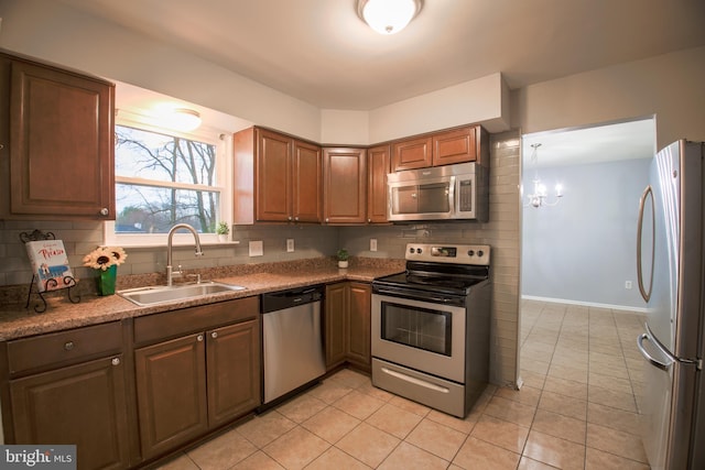 kitchen featuring light tile patterned floors, appliances with stainless steel finishes, backsplash, and a sink