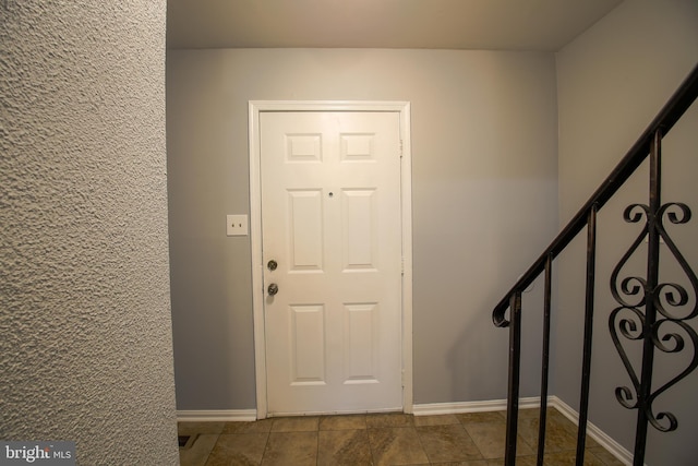 foyer featuring stairway and baseboards