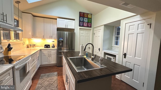 kitchen with sink, stainless steel appliances, wood counters, lofted ceiling with skylight, and a kitchen island with sink