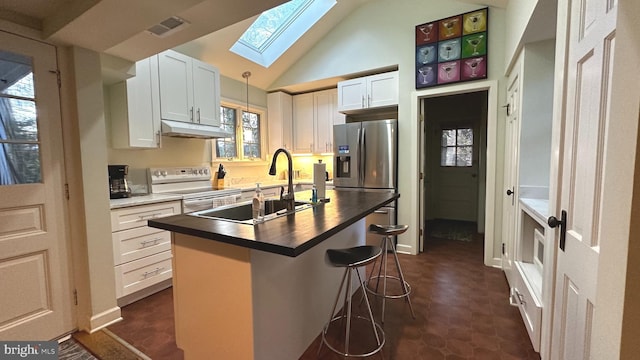 kitchen featuring lofted ceiling with skylight, a center island with sink, sink, electric range, and white cabinetry