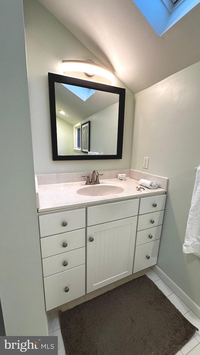 bathroom with vanity, tile patterned floors, and vaulted ceiling with skylight