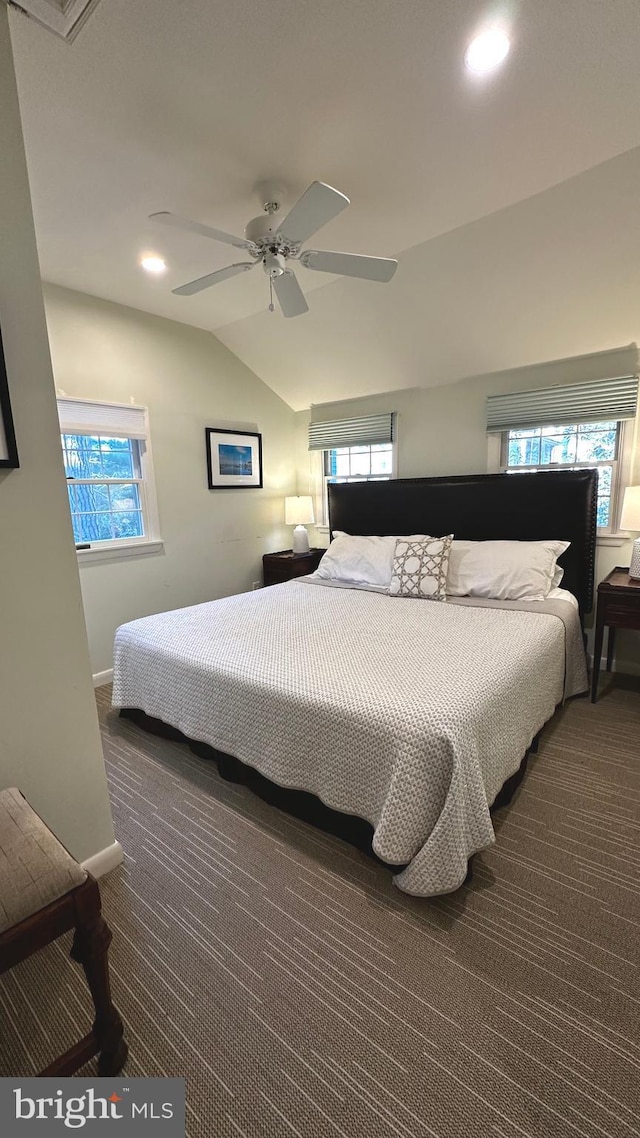 carpeted bedroom with ceiling fan, vaulted ceiling, and multiple windows