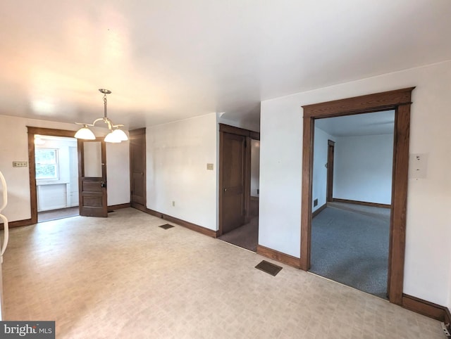 empty room featuring carpet floors and an inviting chandelier