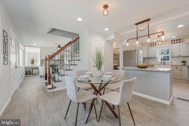 dining space with ceiling fan, light hardwood / wood-style flooring, and sink