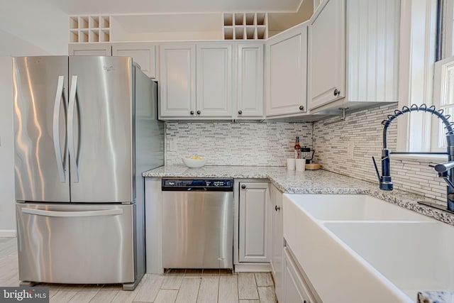 kitchen with white cabinets, sink, decorative backsplash, appliances with stainless steel finishes, and light stone counters