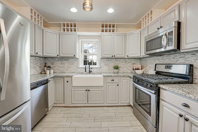 kitchen with white cabinets, stainless steel appliances, light stone counters, and sink