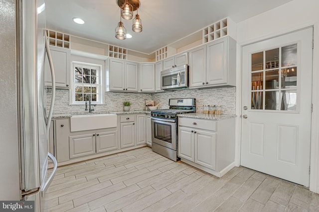 kitchen with sink, decorative backsplash, light stone counters, and stainless steel appliances