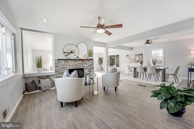 living room featuring ceiling fan and a fireplace