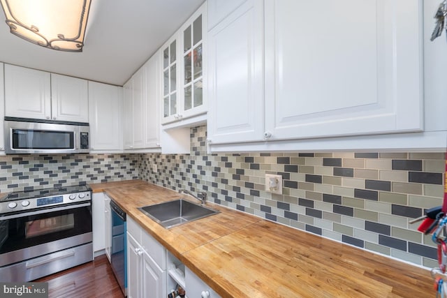 kitchen with sink, white cabinets, wooden counters, and appliances with stainless steel finishes