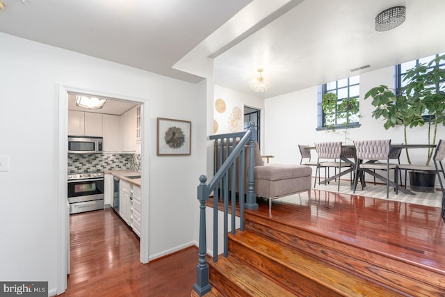 staircase with hardwood / wood-style floors and a chandelier