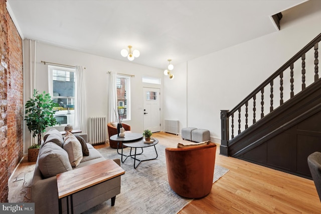 living room with light hardwood / wood-style floors, radiator heating unit, and brick wall