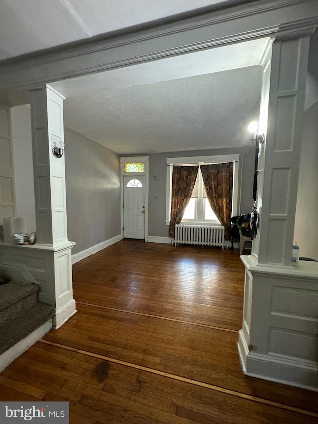 foyer with a textured ceiling, dark hardwood / wood-style flooring, and radiator